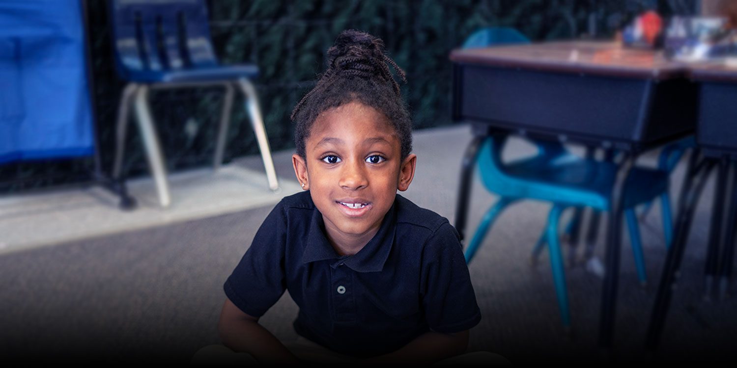 Smiling student sitting on the floor in class